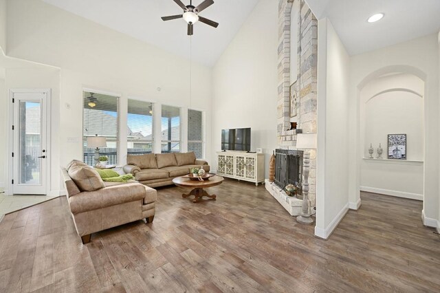 1113 Hartman Dr, Leander, TX 78641 - living room with high vaulted ceiling, a ceiling fan, wood finished floors, a fireplace, and arched walkways