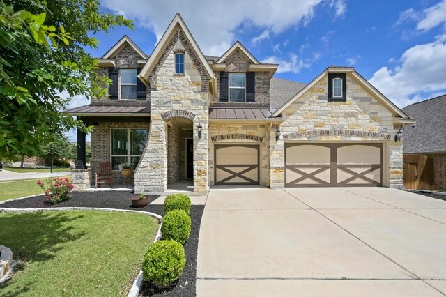 1113 Hartman Dr, Leander, TX 78641 - view of front of home with a standing seam roof, driveway, a front yard, an attached garage, and stone siding