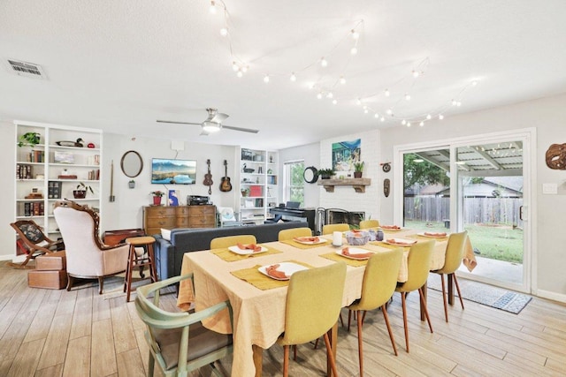 6803 Moonmont Dr, Austin, TX 78745 - dining area featuring a brick fireplace, light wood-style floors, and a ceiling fan