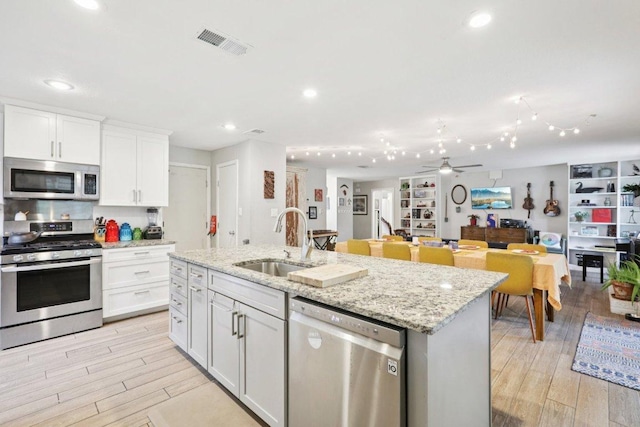 6803 Moonmont Dr, Austin, TX 78745 - kitchen with stainless steel appliances, light wood-style flooring, white cabinets, a ceiling fan, and recessed lighting