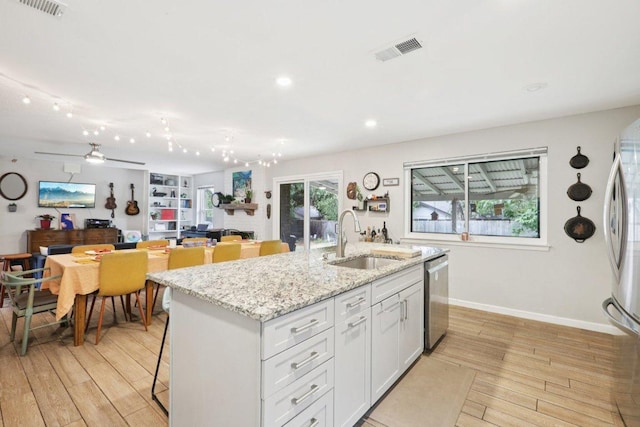6803 Moonmont Dr, Austin, TX 78745 - kitchen with freestanding refrigerator, light wood-style floors, a center island with sink, white cabinetry, and recessed lighting