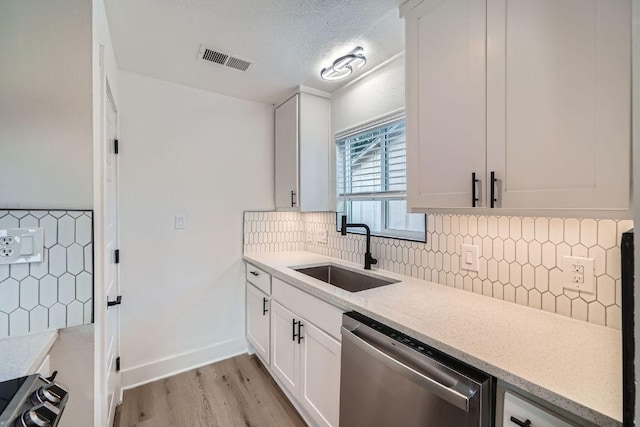 6102 Amber Pass, Austin, TX 78745 - kitchen featuring stainless steel dishwasher, white cabinetry, light wood-style flooring, light stone counters, and a textured ceiling