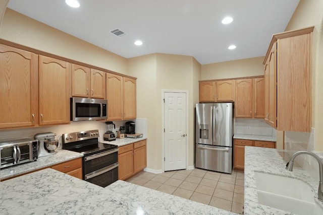 213 S Buffalo Pass, Georgetown, TX 78633 - kitchen featuring appliances with stainless steel finishes, light stone counters, light tile patterned flooring, light brown cabinetry, and recessed lighting