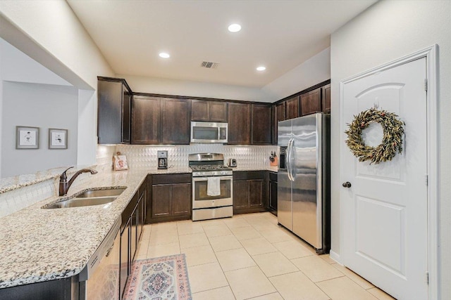 609 Joppa Rd, Leander, TX 78641 - kitchen with appliances with stainless steel finishes, dark brown cabinetry, light stone countertops, tasteful backsplash, and a peninsula