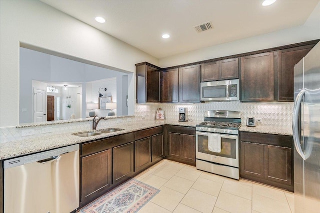 609 Joppa Rd, Leander, TX 78641 - kitchen with stainless steel appliances, dark brown cabinets, tasteful backsplash, light stone countertops, and recessed lighting