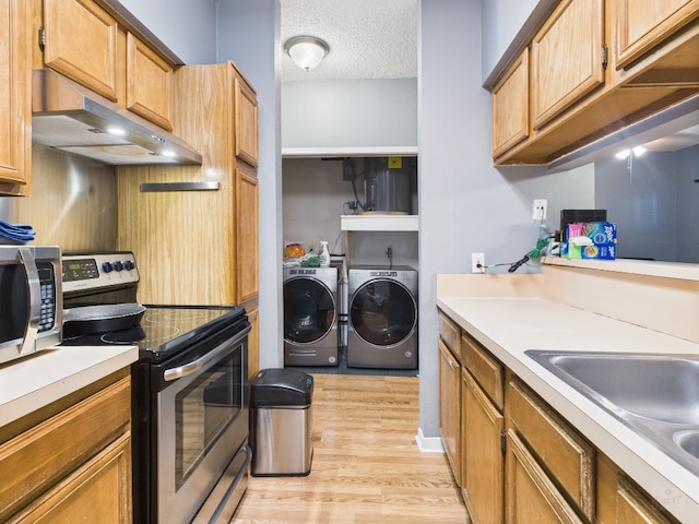2901 San Jacinto Blvd Unit 110, Austin, TX 78705 - kitchen with stainless steel appliances, separate washer and dryer, under cabinet range hood, light wood-type flooring, and light countertops