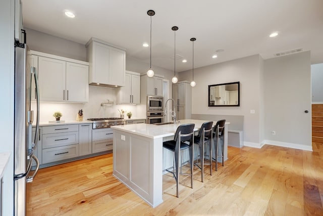 2005 Palo Duro Rd, Austin, TX 78757 - kitchen featuring appliances with stainless steel finishes, light countertops, a kitchen bar, light wood-style floors, and recessed lighting