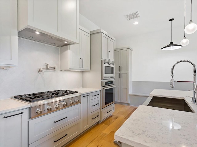 2005 Palo Duro Rd, Austin, TX 78757 - kitchen with appliances with stainless steel finishes, light wood finished floors, light stone counters, and decorative light fixtures