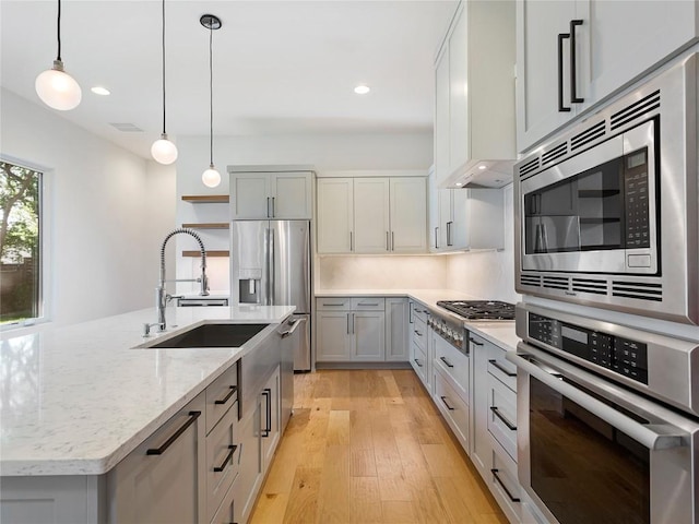 2005 Palo Duro Rd, Austin, TX 78757 - kitchen featuring appliances with stainless steel finishes, light wood finished floors, decorative light fixtures, light stone countertops, and recessed lighting