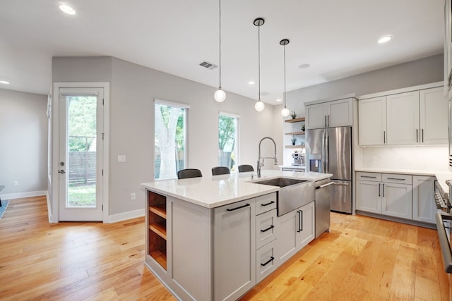 2005 Palo Duro Rd, Austin, TX 78757 - kitchen featuring open shelves, appliances with stainless steel finishes, a kitchen island with sink, pendant lighting, and light wood-style floors