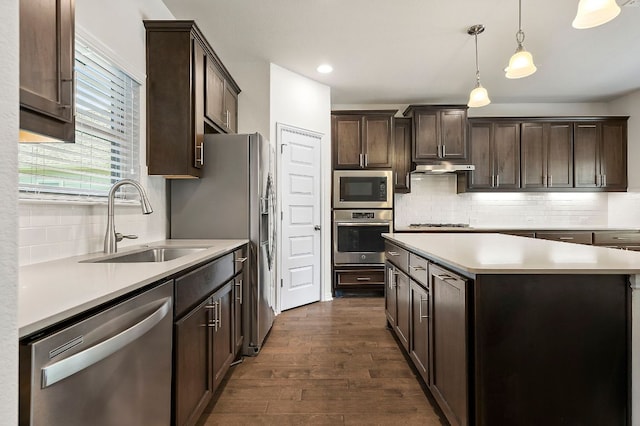 8821 Cattle Baron Path, Austin, TX 78747 - kitchen featuring appliances with stainless steel finishes, dark wood-style flooring, dark brown cabinetry, decorative backsplash, and under cabinet range hood