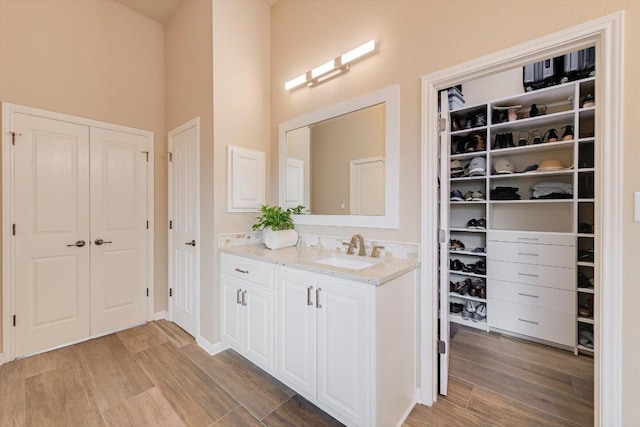 10320 Hansa Cv, Austin, TX 78739 - bathroom with vanity, wood finished floors, a walk in closet, and a towering ceiling