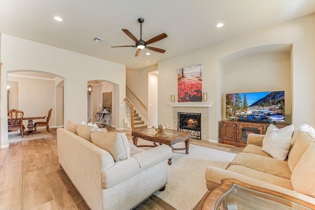 10320 Hansa Cv, Austin, TX 78739 - living room featuring arched walkways, a ceiling fan, light wood-style flooring, recessed lighting, and a tiled fireplace