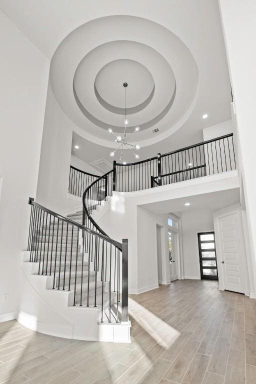 401 Golden Sage Ave, Georgetown, TX 78633 - stairs with a towering ceiling, a raised ceiling, wood finished floors, a chandelier, and recessed lighting
