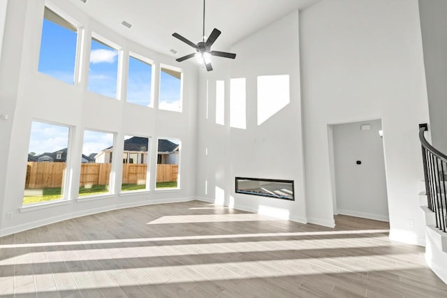 401 Golden Sage Ave, Georgetown, TX 78633 - unfurnished living room featuring a high ceiling, healthy amount of natural light, a glass covered fireplace, a ceiling fan, and stairway