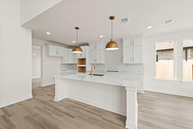 401 Golden Sage Ave, Georgetown, TX 78633 - kitchen with white cabinetry, light wood finished floors, backsplash, a large island with sink, and recessed lighting