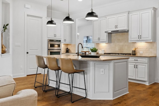 377 Bristlecone Dr, Driftwood, TX 78619 - kitchen featuring appliances with stainless steel finishes, white cabinets, a kitchen breakfast bar, backsplash, and crown molding