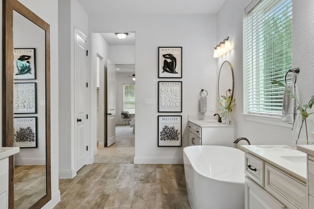 377 Bristlecone Dr, Driftwood, TX 78619 - bathroom featuring wood finished floors, two vanities, a freestanding bath, and a ceiling fan
