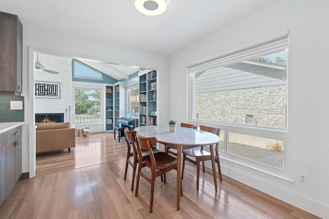 4405 Greystone Dr, Austin, TX 78731 - dining area with lofted ceiling, light wood-type flooring, and a lit fireplace