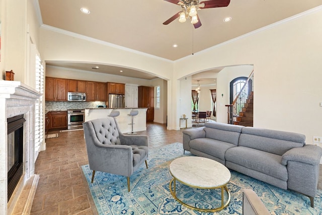 2800 Waymaker Way Unit 63, Austin, TX 78746 - living area with arched walkways, a ceiling fan, crown molding, a glass covered fireplace, and stairs