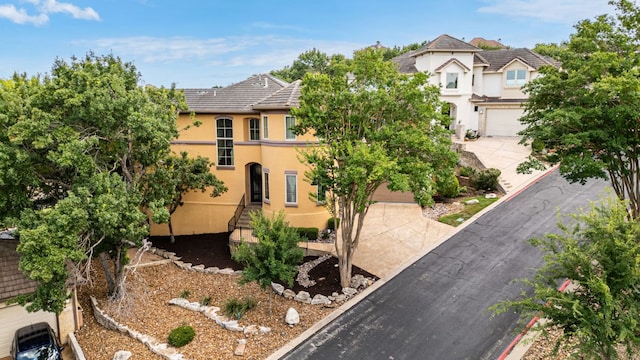 2800 Waymaker Way Unit 63, Austin, TX 78746 - view of front of property featuring stucco siding, driveway, a tile roof, and a garage