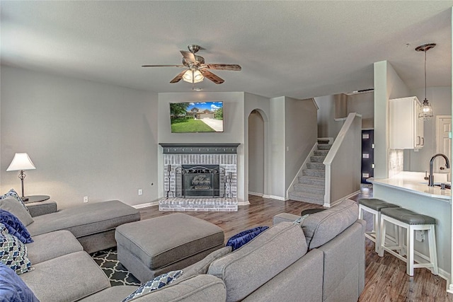 2712 Kickapoo Cavern Dr, Pflugerville, TX 78660 - living room with a ceiling fan, wood finished floors, stairs, and a brick fireplace