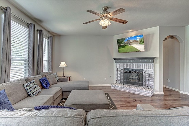 2712 Kickapoo Cavern Dr, Pflugerville, TX 78660 - living room featuring wood finished floors, ceiling fan, a fireplace, and arched walkways