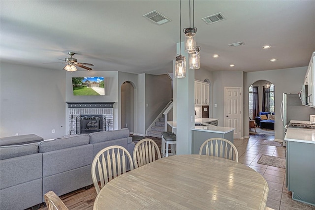 2712 Kickapoo Cavern Dr, Pflugerville, TX 78660 - dining area featuring arched walkways, a ceiling fan, a brick fireplace, stairway, and recessed lighting