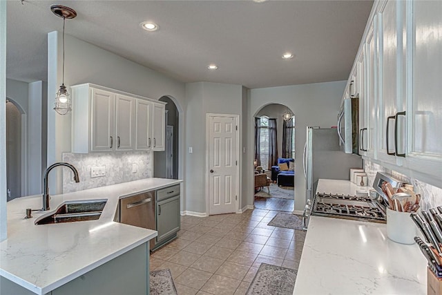 2712 Kickapoo Cavern Dr, Pflugerville, TX 78660 - kitchen with arched walkways, appliances with stainless steel finishes, white cabinets, decorative backsplash, and decorative light fixtures