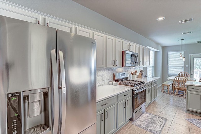 2712 Kickapoo Cavern Dr, Pflugerville, TX 78660 - kitchen with appliances with stainless steel finishes, gray cabinetry, light countertops, decorative backsplash, and pendant lighting