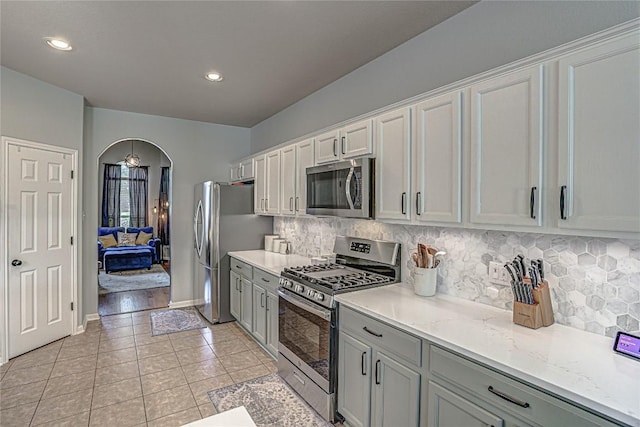 2712 Kickapoo Cavern Dr, Pflugerville, TX 78660 - kitchen with appliances with stainless steel finishes, light tile patterned floors, arched walkways, decorative backsplash, and recessed lighting