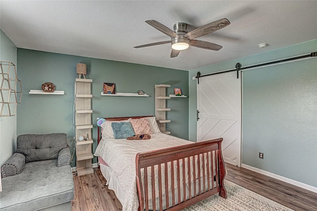 2712 Kickapoo Cavern Dr, Pflugerville, TX 78660 - bedroom featuring a barn door, wood finished floors, and a ceiling fan