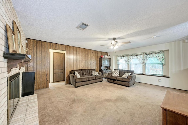 6606 Lancret Hill Dr, Austin, TX 78745 - living room featuring a brick fireplace, ceiling fan, wooden walls, a textured ceiling, and light carpet