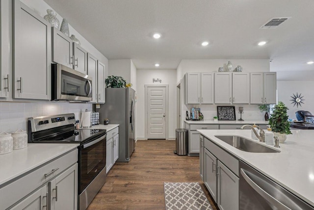 111 Krause Springs Dr, Hutto, TX 78634 - kitchen featuring stainless steel appliances, light countertops, dark wood-style floors, decorative backsplash, and recessed lighting