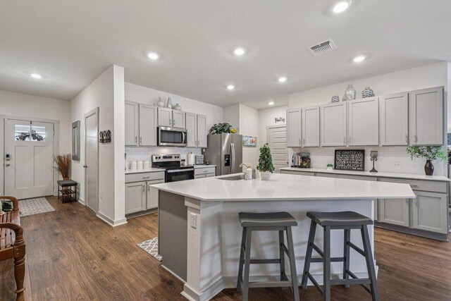 111 Krause Springs Dr, Hutto, TX 78634 - kitchen featuring appliances with stainless steel finishes, an island with sink, a breakfast bar, dark wood finished floors, and recessed lighting
