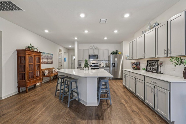 111 Krause Springs Dr, Hutto, TX 78634 - kitchen featuring stainless steel appliances, gray cabinets, recessed lighting, dark wood finished floors, and a breakfast bar