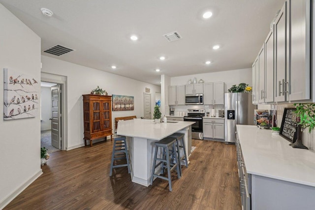 111 Krause Springs Dr, Hutto, TX 78634 - kitchen with appliances with stainless steel finishes, dark wood-style flooring, a breakfast bar, gray cabinets, and recessed lighting