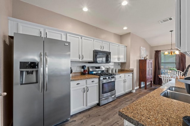 1111 Whitley Dr, Leander, TX 78641 - kitchen featuring appliances with stainless steel finishes, dark wood-style flooring, backsplash, white cabinetry, and vaulted ceiling