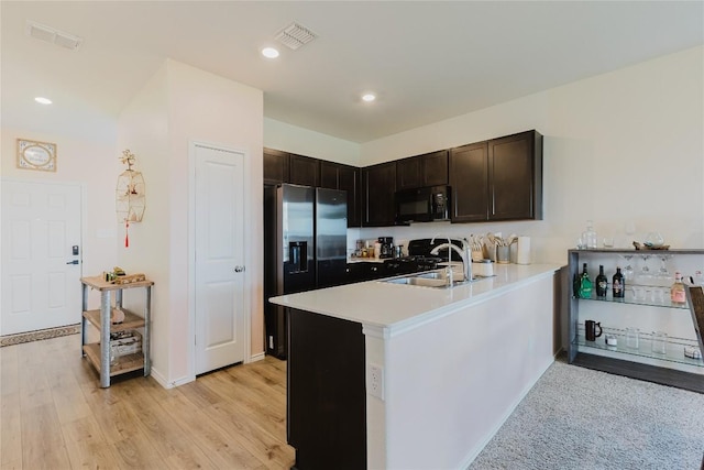 504 N Thunderstorm Ave, Lockhart, TX 78644 - kitchen with black microwave, a peninsula, light countertops, dark brown cabinetry, and stove