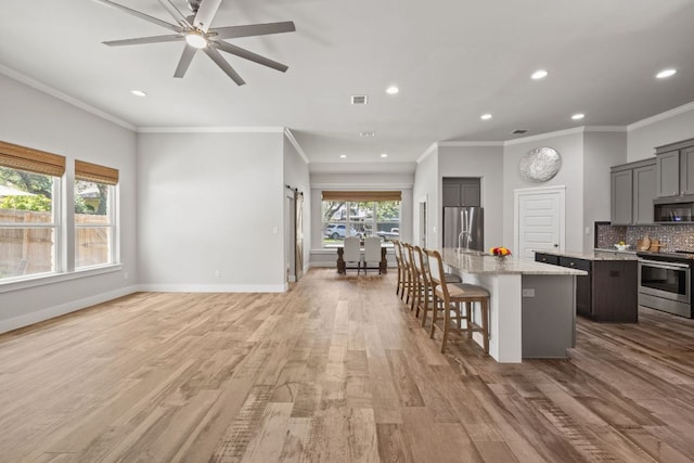 4 Country Ct, Wimberley, TX 78676 - kitchen with appliances with stainless steel finishes, a kitchen island with sink, light wood-style floors, gray cabinets, and recessed lighting