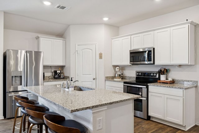 1004 Norway, Seguin, TX 78155 - kitchen featuring appliances with stainless steel finishes, dark wood-style floors, a kitchen island with sink, white cabinets, and recessed lighting