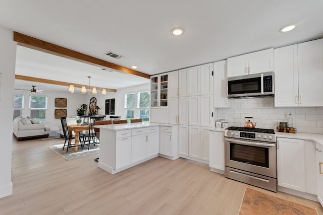 215 Paulus St, Schulenburg, TX 78956 - kitchen with stainless steel appliances, a peninsula, healthy amount of natural light, beamed ceiling, and light countertops
