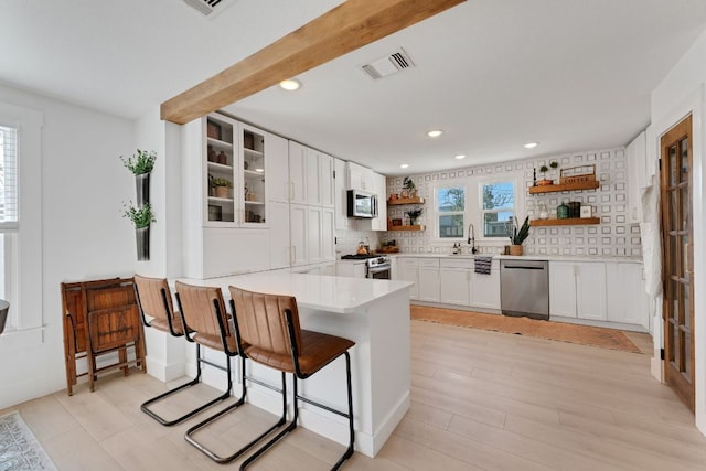 215 Paulus St, Schulenburg, TX 78956 - kitchen with stainless steel appliances, open shelves, a peninsula, white cabinets, and tasteful backsplash
