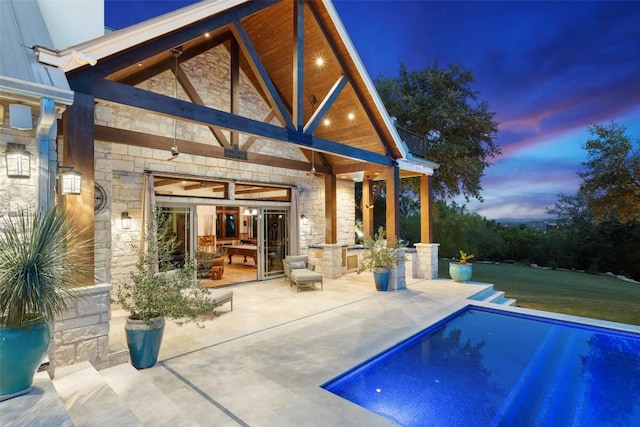601 Crystal Creek Dr, Austin, TX 78746 - back of property featuring stone siding, an outdoor pool, and a patio area