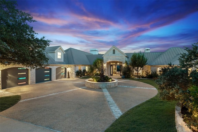 601 Crystal Creek Dr, Austin, TX 78746 - french country style house featuring stone siding, curved driveway, a metal roof, and a chimney