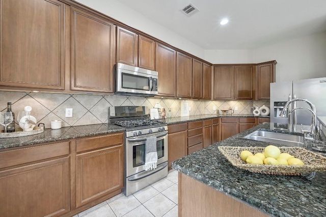 250 Lexington Dr, Austin, TX 78737 - kitchen with stainless steel appliances, dark stone countertops, light tile patterned floors, and backsplash