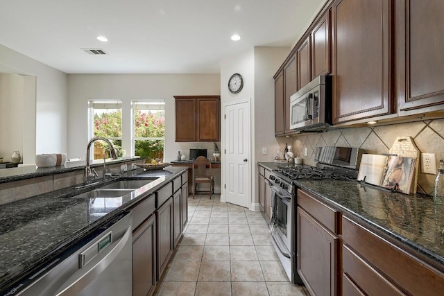 250 Lexington Dr, Austin, TX 78737 - kitchen with stainless steel appliances, decorative backsplash, dark stone counters, light tile patterned floors, and recessed lighting