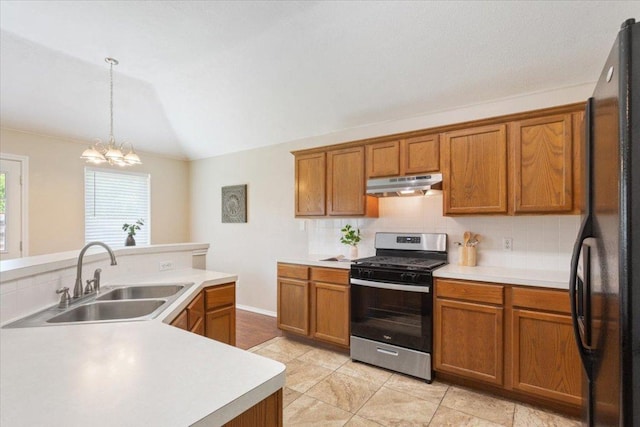 1811 Indian Summer Pass, Round Rock, TX 78665 - kitchen featuring gas stove, under cabinet range hood, freestanding refrigerator, brown cabinetry, and tasteful backsplash