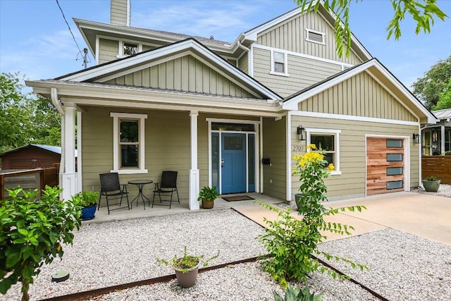 2707 La Mesa Dr, Austin, TX 78704 - view of front facade featuring a porch, board and batten siding, concrete driveway, a chimney, and a garage