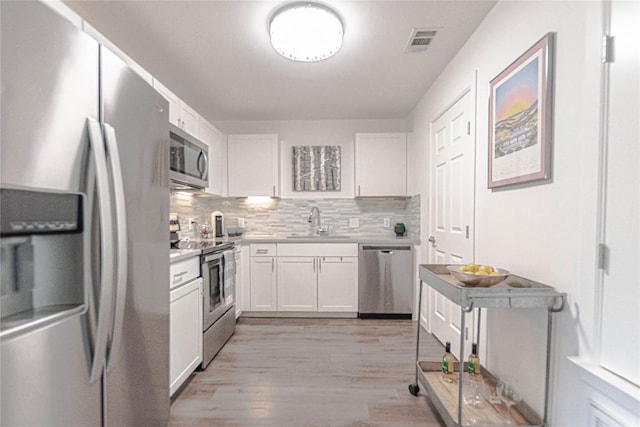 3604 Clawson Rd Unit 204, Austin, TX 78704 - kitchen featuring appliances with stainless steel finishes, white cabinetry, light wood-type flooring, and light countertops
